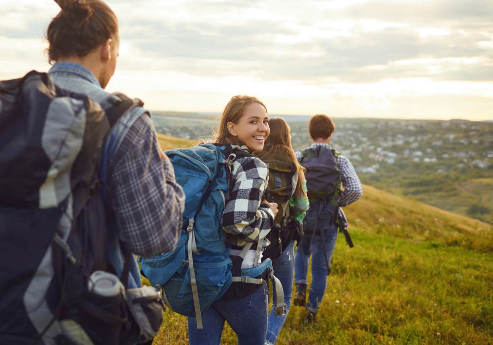 Junge Gruppe von vier Personen, die gut gelaunt durch die Natur wandern